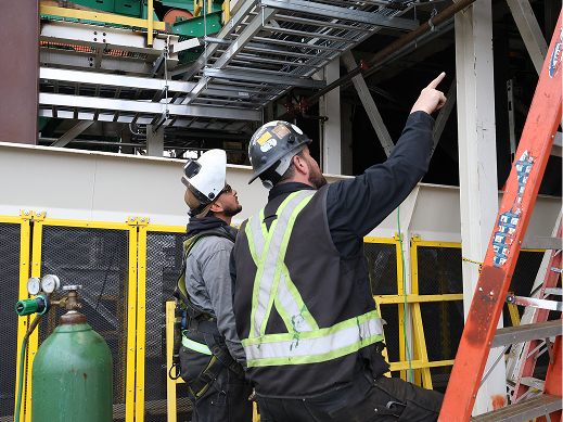 Crew discussing live commissioning readings beside operating industrial equipment